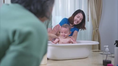Smiling Family Bathing Baby at Home