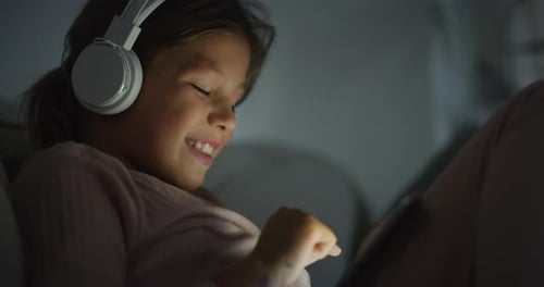 Close Up of a Little Girl Using Headphones and Digital Tablet to Play Game