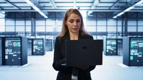 Software Developer Walking in Data Center with Laptop