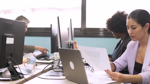 Colegas multiétnicos trabalhando em computadores no espaço de trabalho do escritório