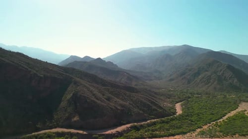 Aerial view drone flying over scenic rocky mountains with a clear blue sky.