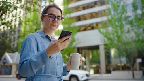 Caucasian Woman in Glasses Walking Around the City and Using Smartphone