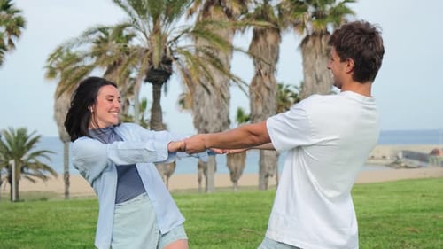 Smiling Couple Holding Hands Spinning on Beach Park