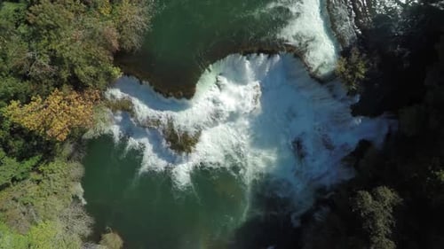 Luftaufnahme des majestätischen Wasserfalls, der in einen tiefgrünen Fluss mündet