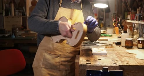 Violinmaker coating the ribs of a new handcrafted violin in his workshop in Cremona, Italy