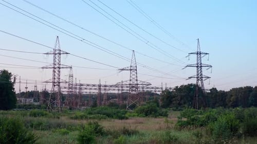 Lots of electricity towers on field. Large power station with many high-voltage electric lines