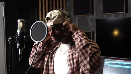 Young male singer recording music in professional studio