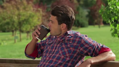 Man Relaxes With Coffee on Park Bench