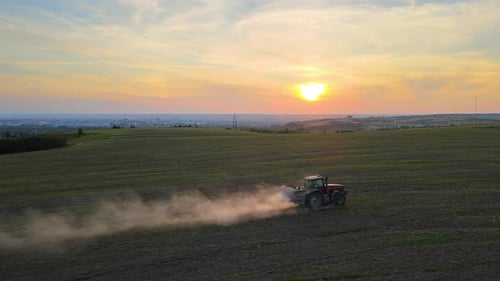 Tractor Spraying Fertilizers with Insecticide Herbicide Chemicals on Agricultural Field at Sunset