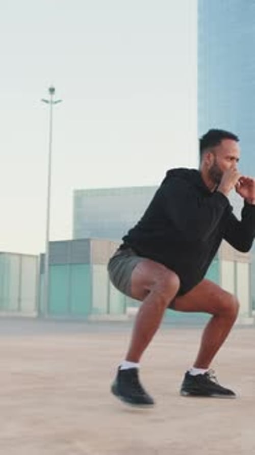 Young athlete doing workout, squats and jumping on the waterfront