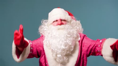 Dancing Santa Claus with Red Nose on Blue Studio Background in Red Gloves with a White Lush Beard