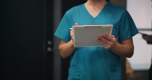 Medical Professional Writes on Clipboard in Hospital