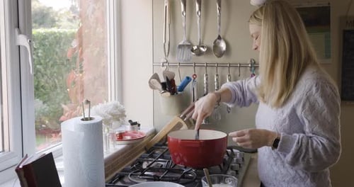 Kitchen, cooking and food with a woman in her home, preparing a meal for lunch or dinner on a stove