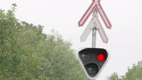 Sinal de travessia ferroviária com luzes vermelhas piscando.