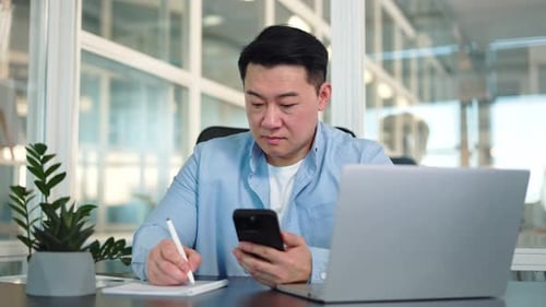 Beschäftigter kopiert Informationen vom Handy in den Notizblock im Büro
