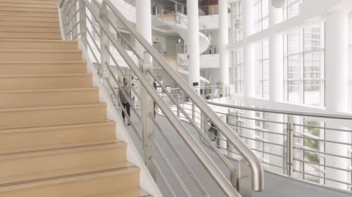 Businesswoman and Businessman Walking in Modern Atrium Building