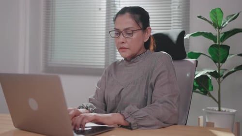 Close-up of woman using computer thinking while checking budget on screen working in office.
