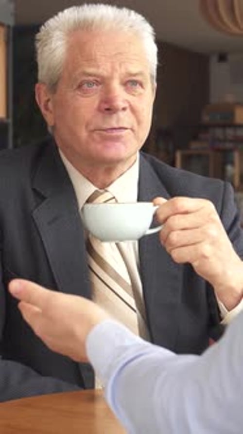 Senior Man Drinking Coffee in Business Meeting