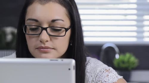 Young Woman Using Tablet Computer in Bright Kitchen