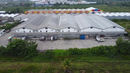Aerial view of a goods distribution warehouse lined up with goods trucks parked in front of the ware