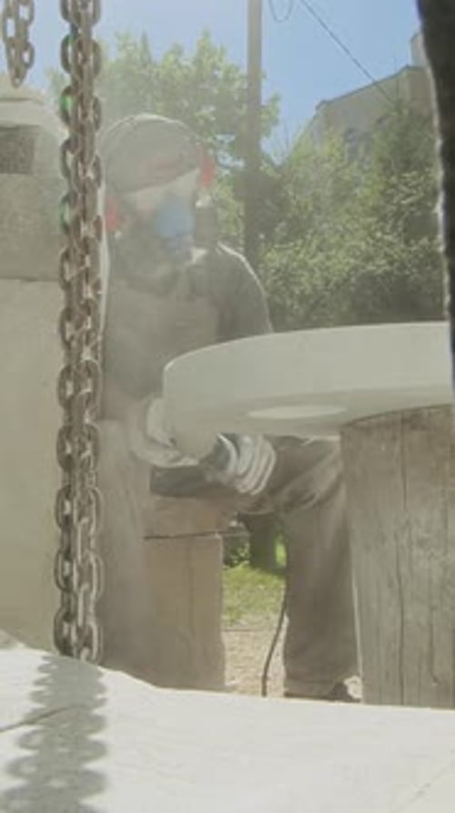 Vertical of Male Artisan Grinding Porcelain Stoneware Piece Outdoors