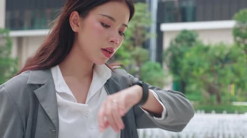 Young Woman Using Smartwatch in City Park