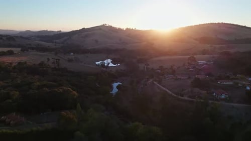 Countryside aerial shot of scenic orange sunset panning down and showing the river with trees