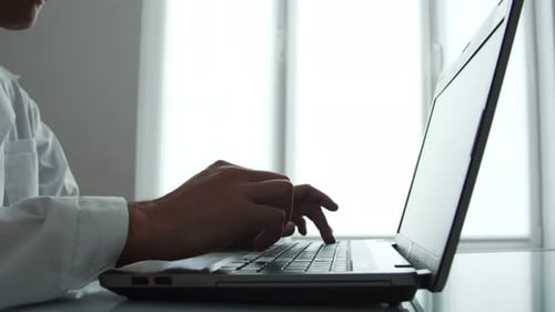 Person Typing on Laptop Computer, Wearing Lab Coat
