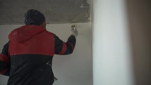 Man Applies Putty to Interior Wall Seam