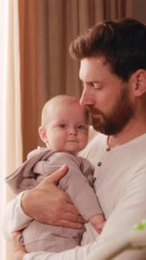 Man Holding Infant in Sunny Interior Room