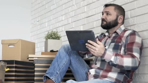 Young, Man with Tablet Computer Sitting on Floor at Her New Home 40s