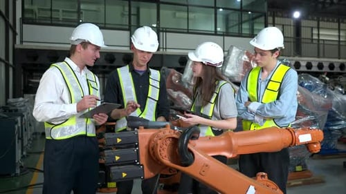 Gruppe von Ingenieuren und Technikern, die in einer Roboterarmfabrik zusammenarbeiten. Inspektion des Roboterarms