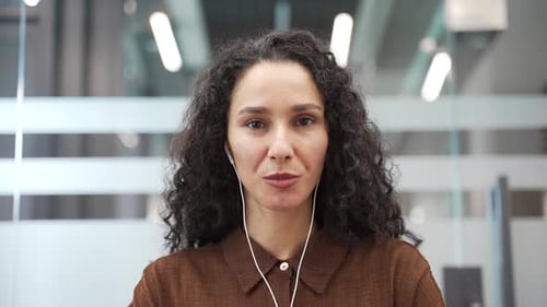 Webcam view. Businesswoman in headphones talking on video call conference looking at camera in offic