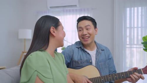 Man Plays Guitar for Woman at Home