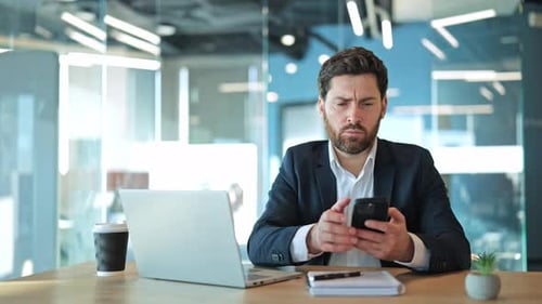 Professional Man Checking Smartphone at Office Desk