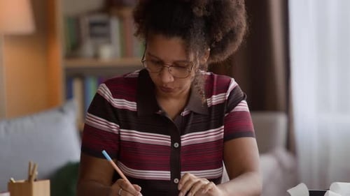 Young Woman with Pen and Calculator Doing Paperwork at Home