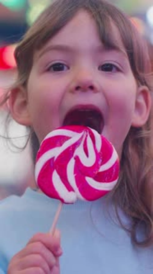 Child Enjoys a Red and White Swirl Lollipop