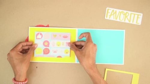 Hands Crafting and Decorating a Colorful Scrapbook Page