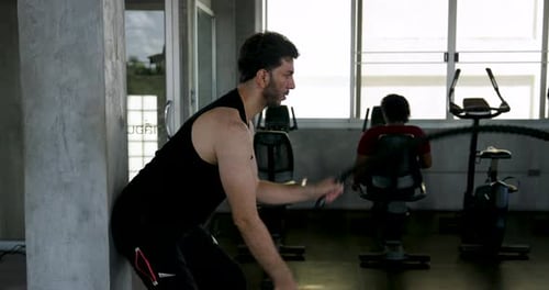 Man Performing Intense Battle Rope Workout in a Gym