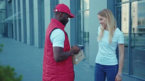 Shot of African American Delivery Man Hold Package Woman Client Paying By Phone for Parcel