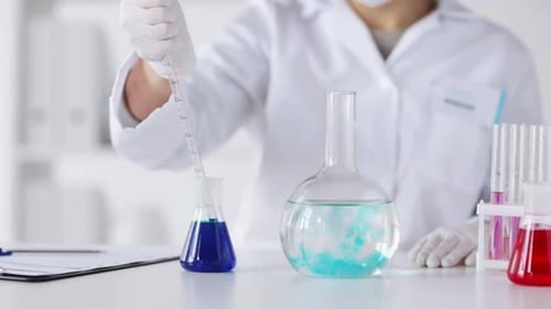 Scientist Drops Liquid into Beaker in Laboratory