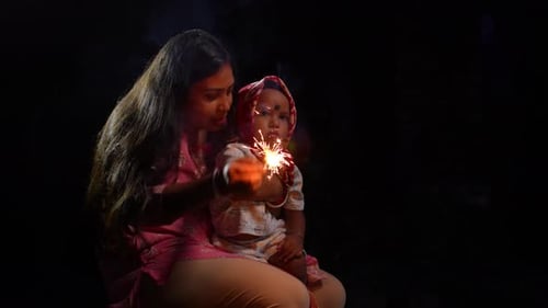 Woman and Baby Holding Sparkling Firework at Night