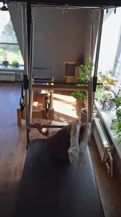 Woman Doing Pilates Exercises with Instructor on Balanced Body Cadillac Machine at Studio Focusing