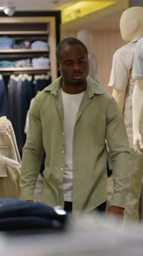 African American Customer Choosing Clothes in Fashion Store with Discount