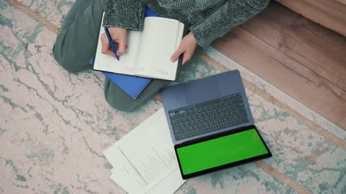 Woman Studying at Home Taking Notes with a Green Screen Laptop