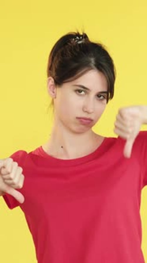 Woman Gesturing Disapproval Against Yellow Background