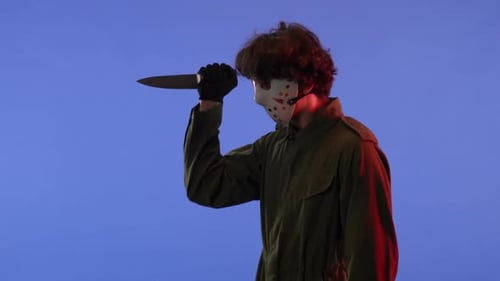 Man in White Mask with Big Sharp Knife on Blue Background with Red Neon Light Image of Jason