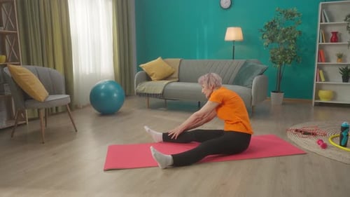 Senior Woman Stretching on Exercise Mat at Home