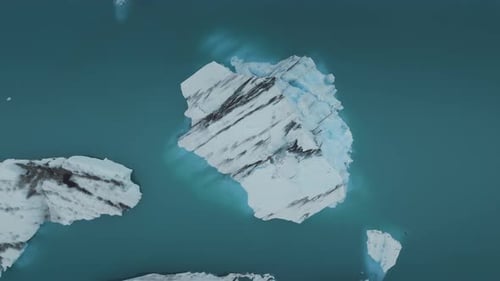 Luftaufnahme eines großen Eisbergs in der Mitte eines großen Gletschersees von oben nach unten.