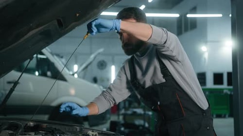Caucasian 30s Man Opening Car Hood in Repair Workshop Check Engine Oil Level at Auto Service Male